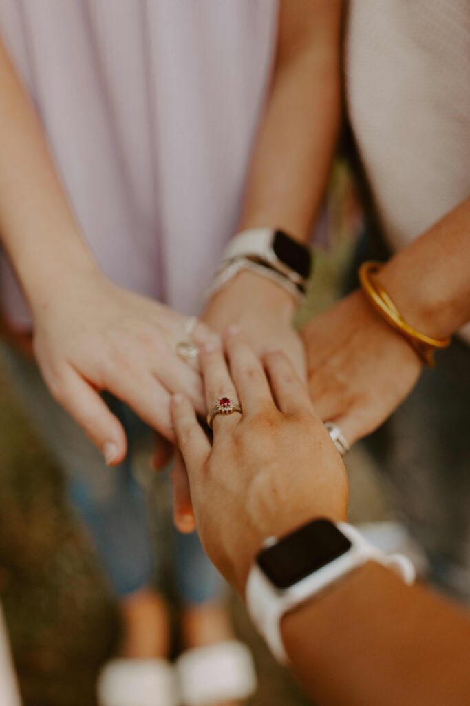 An image of four hands placed on top of each other gently as a sign of working together as a team